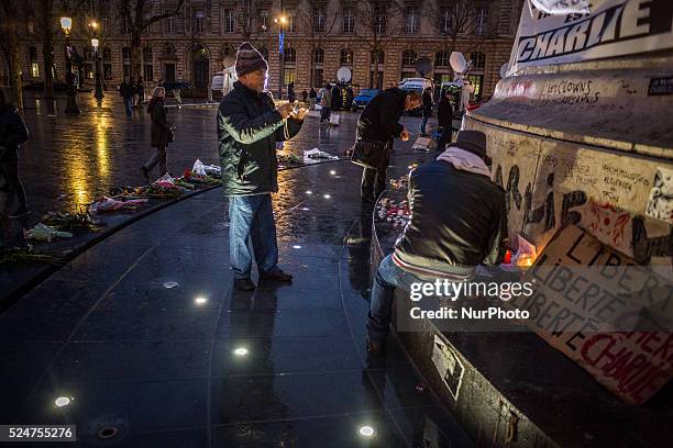 People gather to light candles, give wreath of flowers and write on the wall of Republic Square, Paris on January 13 after the killing of the past...