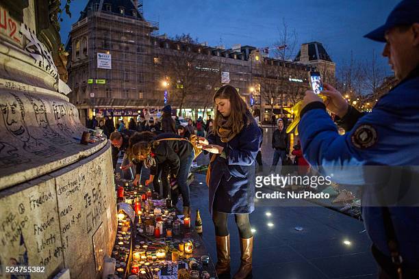 People gather to light candles, give wreath of flowers and write on the wall of Republic Square, Paris on January 13 after the killing of the past...