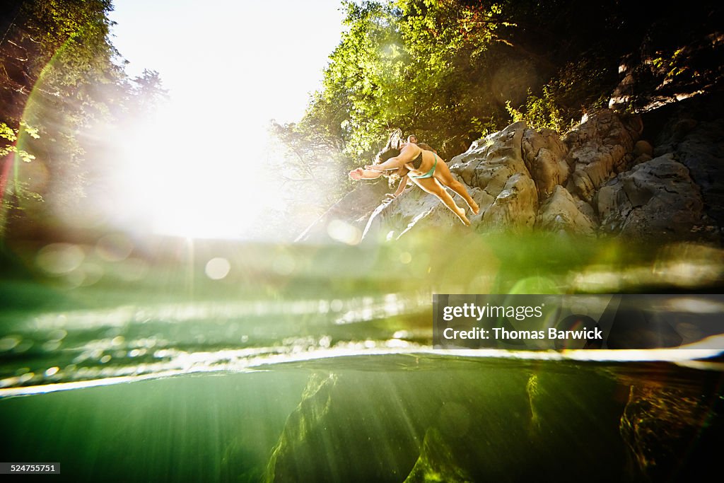 Woman diving off of boulder into river