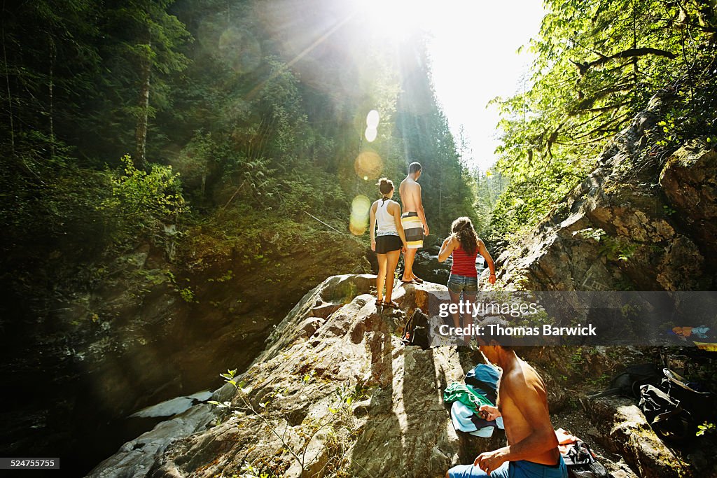 Friends walking up boulder overlooking river