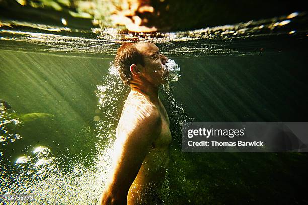 man swimming to surface of river underwater view - auftauchen wasser stock-fotos und bilder