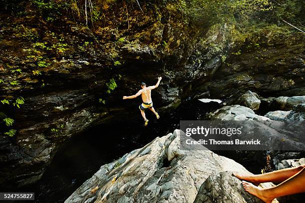 man jumping into swimming hole arms outstretched - diving risk stock-fotos und bilder