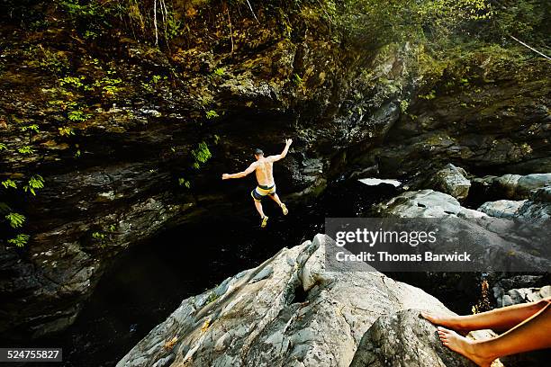 man jumping into swimming hole arms outstretched - wonderlust stock pictures, royalty-free photos & images