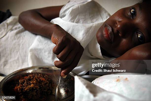 Juolith Dreusonne who suffers from both HIV and Tuberculosis eats a meal in her bed before checking out of Zanmi Lasante Hospital March 24, 2005...