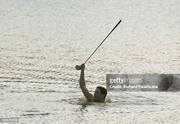 Golf fan Kelly Shields retrieves Woody Austin's driver from the lake after Austin threw it in from the 18th tee during the first round of The Players...