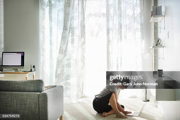 woman sitting on floor using laptop . - norman window fotografías e imágenes de stock