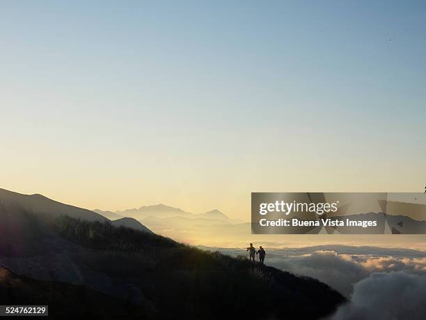 couple on a mountain slope over fog - distant stock pictures, royalty-free photos & images