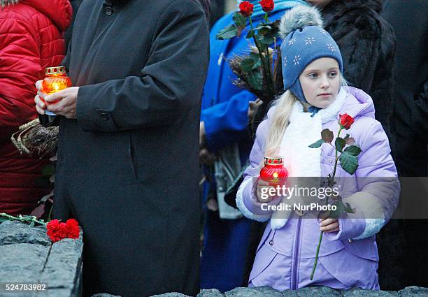 Ukrainian girl attend a memorial ceremony near a monument to the victims of the Great Famine in Kiev, Ukraine,28 November 2015. Ukrainians light...