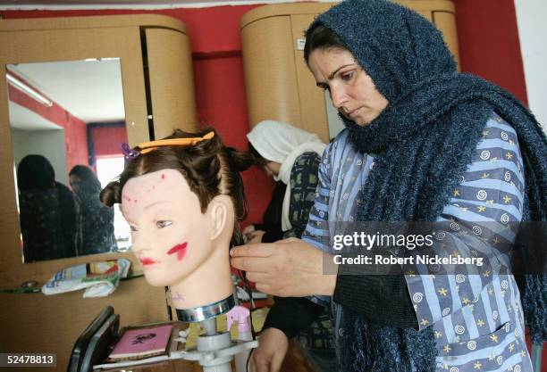 An Afghan woman practices on a mannequin head at Debbie Rodriguez's Oasis Beauty School February 13, 2005 in Kabul, Afghanistan. Rodriguez operates...