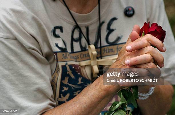 Woman clasps a rose as she joins others in prayer during a mass that was celebrated outside the Woodside hospice grounds where brain-damaged Florida...