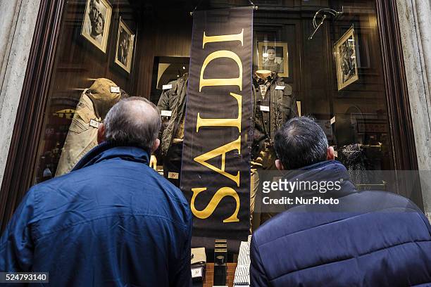 People walk past a shop window offering discounts during the winter sales in downtown Rome, Italy, on January 5, 2016. The first day of winter sales...