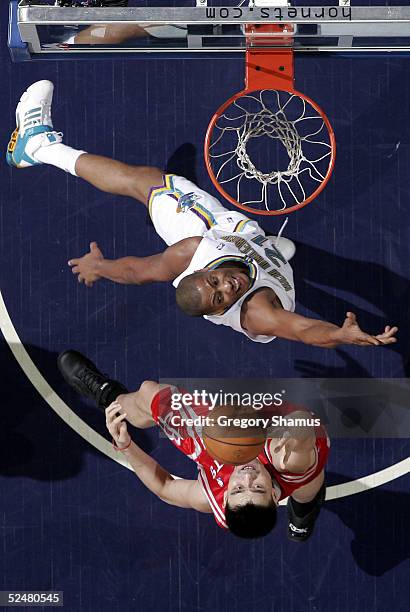 Yao Ming of the Houston Rockets tries to get a shot off over Jamaal Magloire of the New Orleans Hornets at the New Orleans Arena on March 25, 2005 in...