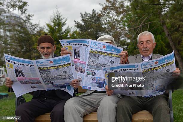 Three men on a bench outside Aksaray Grand Mosque read the TUR Journal ahead of the third stage of the 52nd Presidential Tour of Turkey 2016, Aksaray...