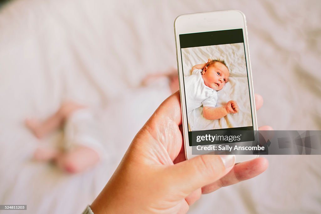 Mother taking a smartphone picture of her baby