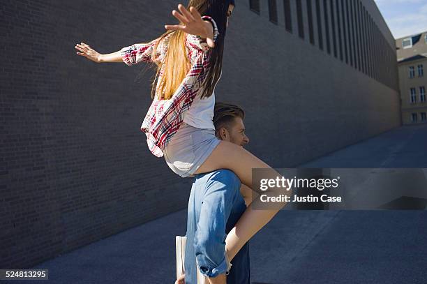 man carries a woman on his shoulders in the street - huckepack nehmen stock-fotos und bilder