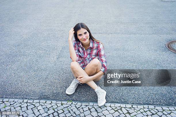 woman smiling and sitting on the street - horizontal fotos stock-fotos und bilder