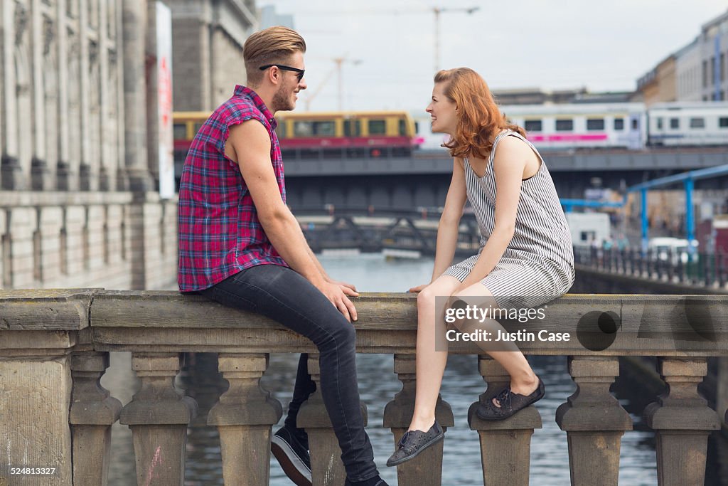 A couple is sitting on a city bridge