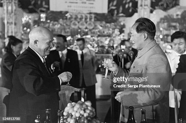 Nikita Khrushchev and Mao Tse Tung toast each other.