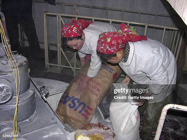 In this handout photo from the World Food Programme, North Korean workers empty sacks of milk into a mixing vat at a factory supported by the UN WFP...