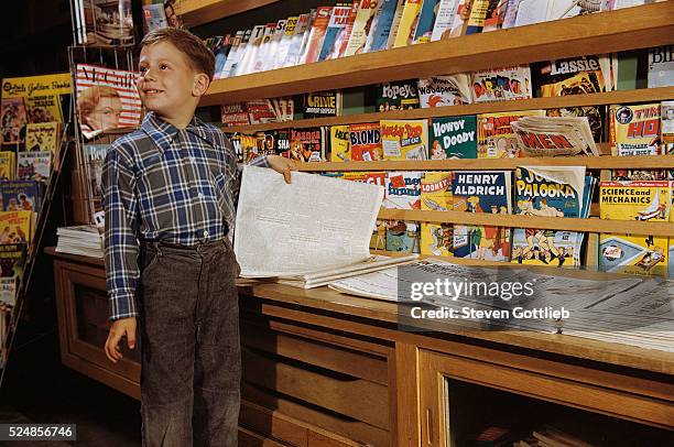 Boy Holding Paper in Newsstand