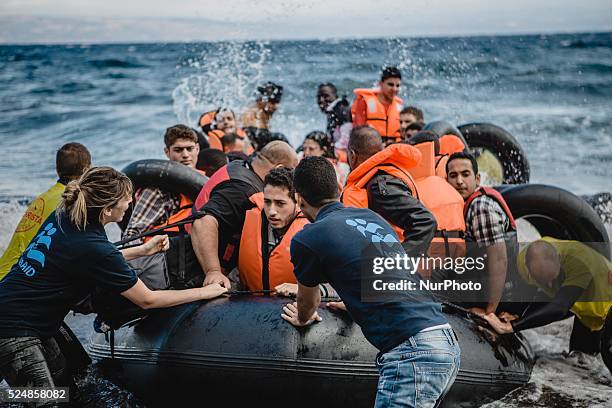 Volunteers help migrants embark from the dinghy they have arrived on, in Lesbos, on September 30, 2015.