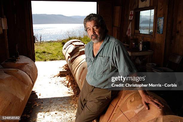 Guujaaw, President of the Haida Nation and a carver, in a carving shed in Skidegate with a totem pole that he's carving.