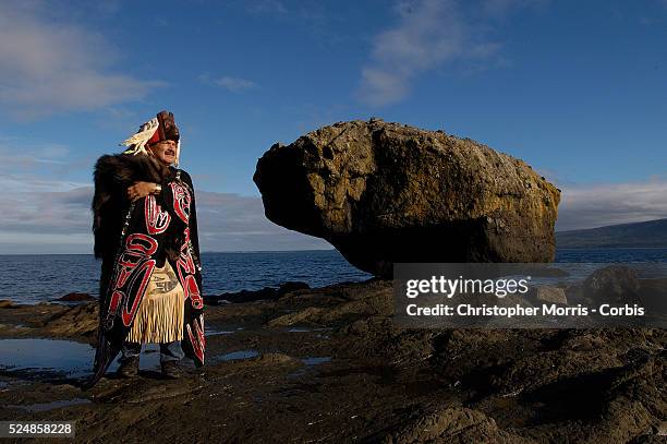 Hereditary Chief Roy Jones Jr., in his ceremonial headdress and costume, stands next to Balance Rock on the shore of Skidegate Inlet outside the...