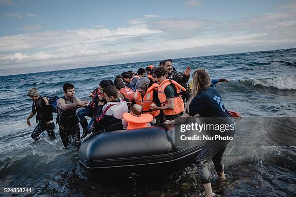 Volunteers help migrants embark from the dinghy they have arrived on, in Lesbos, on September 30, 2015.