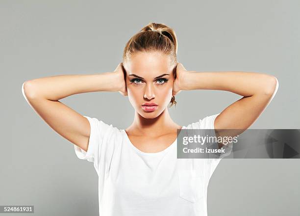 young woman covering ears with hands - word of mouth stock pictures, royalty-free photos & images