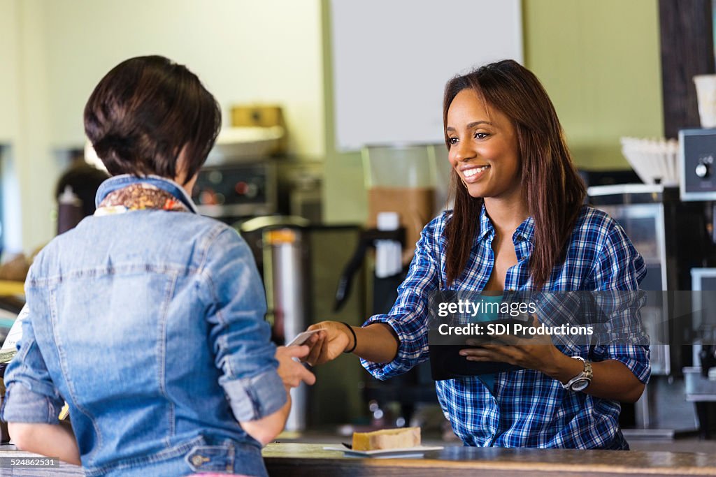 Shop employee accepting payment on digital tablet credit card reader
