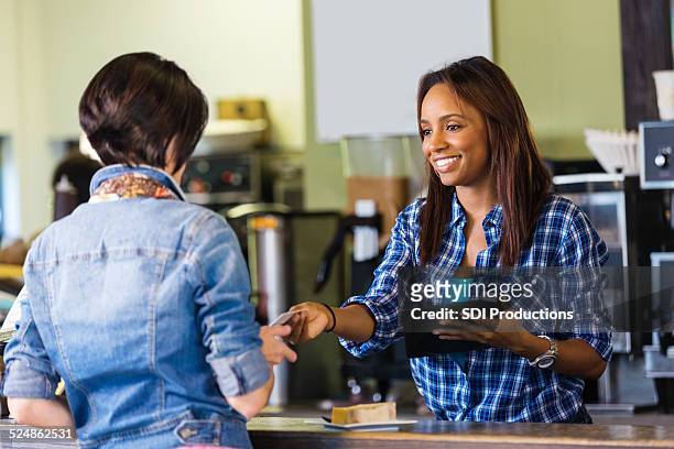 shop employee accepting payment on digital tablet credit card reader - debit cards credit cards accepted stock pictures, royalty-free photos & images