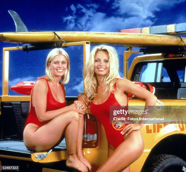 Portrait of American actresses Nicole Eggert and Pamela Anderson, stars of the tv series 'Baywatch,' wearing low-cut red swimsuits, 1992.