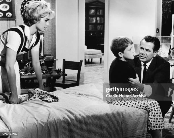 Glenn Ford soothes his sick son, played by Ron Howard , as Shirley Jones looks on in a film still from the motion picture 'The Courtship of Eddie's...