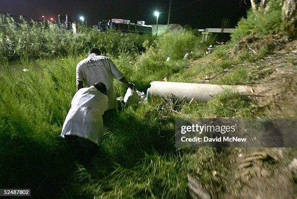 Man leads his shivering and exhausted female companion after emerging from the New River, reportedly the most polluted river in the US, as they hide...