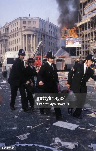 Police officers carry away a protester during the Poll Tax riot in Trafalgar Square, London, 31st March 1990.