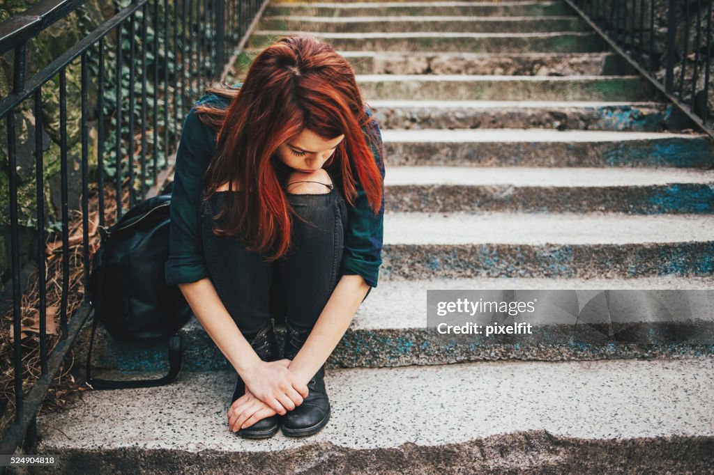 Sad lonely girl sitting on stairs