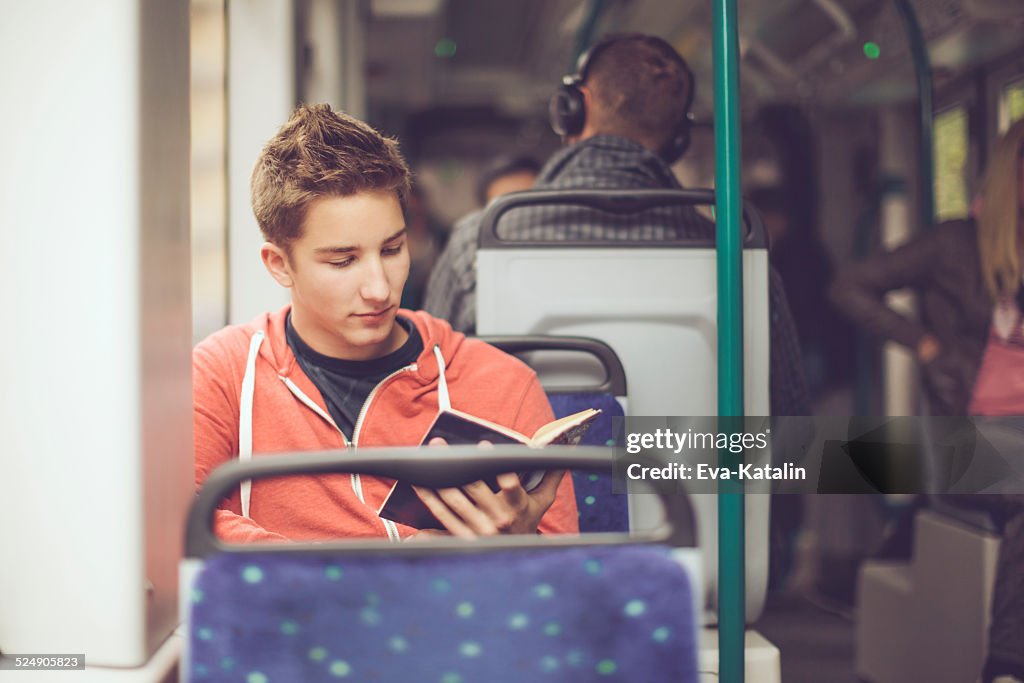 Teenage boy reading a book on the tram