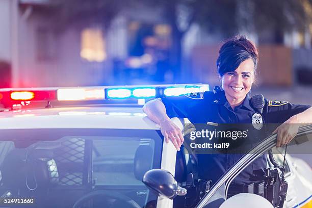 female police officer standing next to patrol car - politiedienst stockfoto's en -beelden