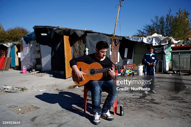 Boy plays the guitar in a shanty town near fuencarral train station in Madrid as they wait to the city council machinery to demolish their shacks in...