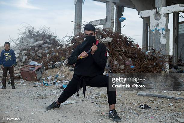 Palestinian youth holds sword as he practice Ninja Martial Arts skills between the rubble of destroyed houses at Al Nada towers northern the Gaza...