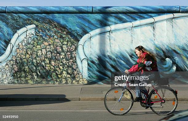 Cyclist rides past a still-standing section of the Berlin Wall known as the East Side Gallery on March 30, 2005 in Berlin, Germany. According to a...