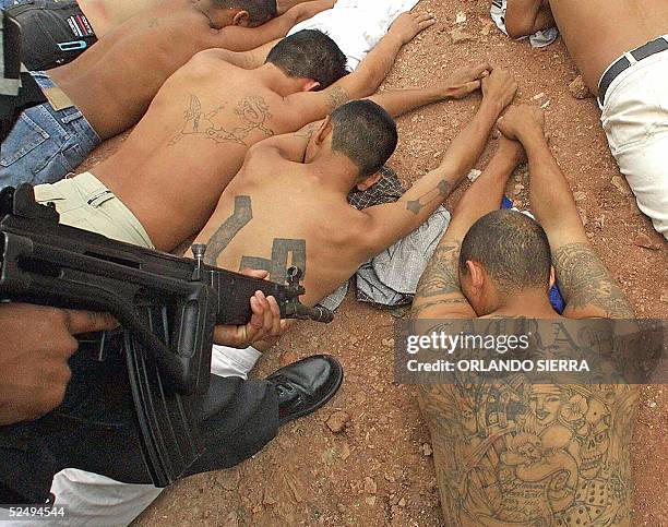 Members of the gang Mara 18, are guarded by a police officer in Tegucigalpa, Honduras, 02 July 2003. Violence from street gangs, known in the region...