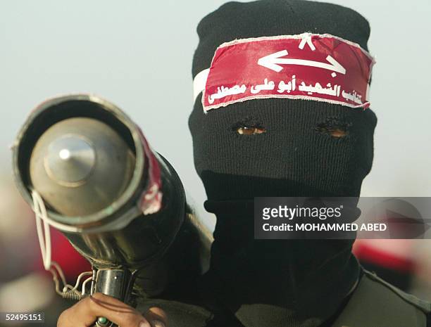 Masked Palestinian militant from the Marxist Popular Front of the Liberation of Palestine takes part in an anti-Israel rally at the Bureij refugee...