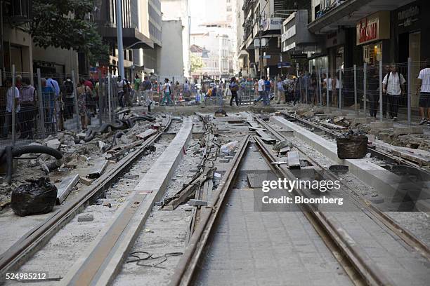 Pedestrians walk past newly laid tracks for a light rail system in downtown Rio de Janeiro, Brazil, on Friday, April 15, 2016. The rail system will...