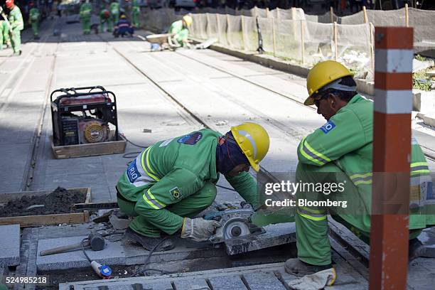 Worker cuts paving stones during construction of a light rail system in downtown Rio de Janeiro, Brazil, on Friday, April 15, 2016. The rail system...