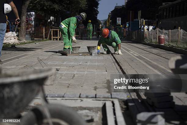 Workers lay paving stones during construction of a light rail system in downtown Rio de Janeiro, Brazil, on Friday, April 15, 2016. The rail system...