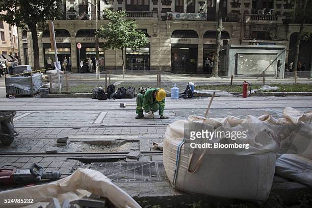 Worker lays paving stones during construction of a light rail system in downtown Rio de Janeiro, Brazil, on Friday, April 15, 2016. The rail system...