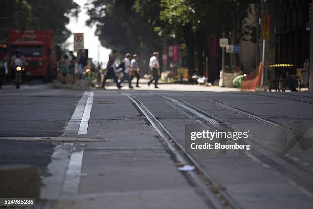 Pedestrians cross newly laid rails for a light rail system in downtown Rio de Janeiro, Brazil, on Friday, April 15, 2016. The rail system will...