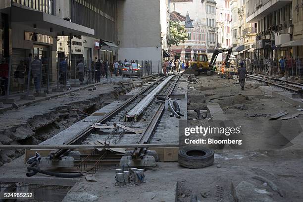 Pedestrians walk near newly laid tracks for a light rail system in downtown Rio de Janeiro, Brazil, on Friday, April 15, 2016. The rail system will...