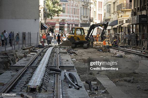 Pedestrians walk near newly laid tracks for a light rail system in downtown Rio de Janeiro, Brazil, on Friday, April 15, 2016. The rail system will...